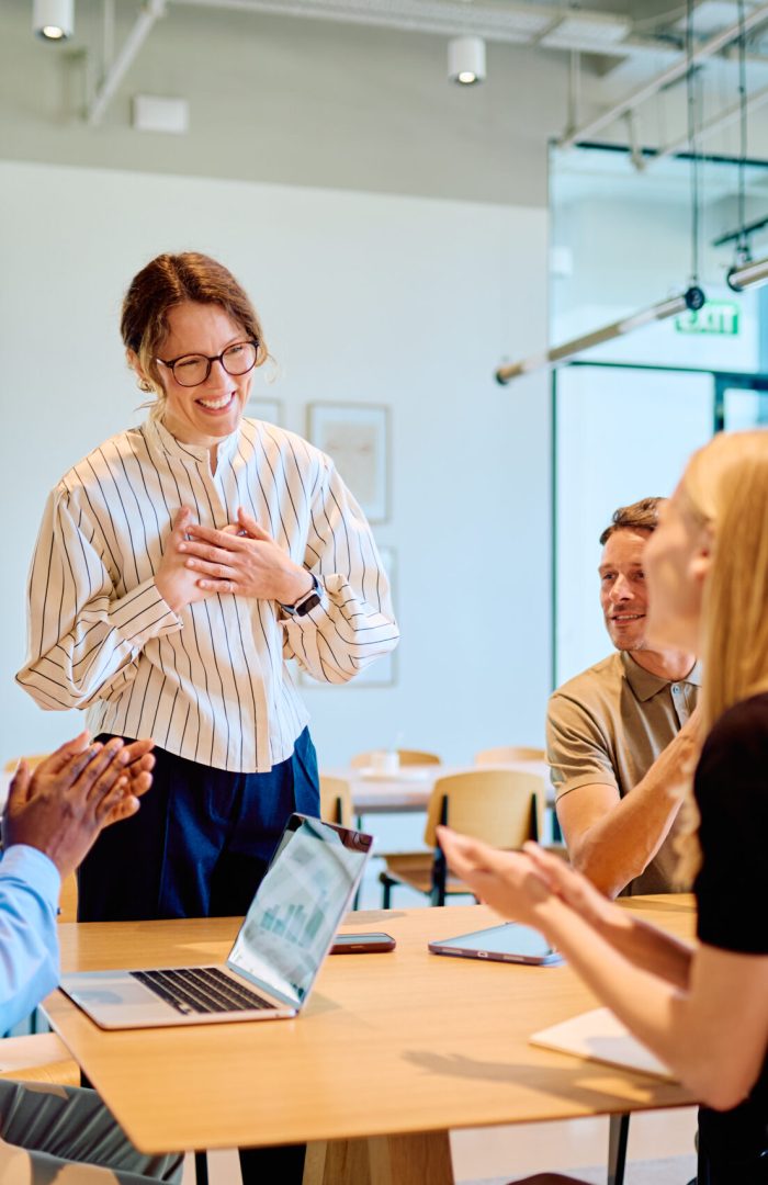 Colleagues applauding team member receiving recognition