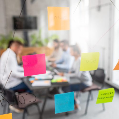 Business people meeting at office and use post it notes to share idea. Brainstorming concept. Sticky note on glass wall.