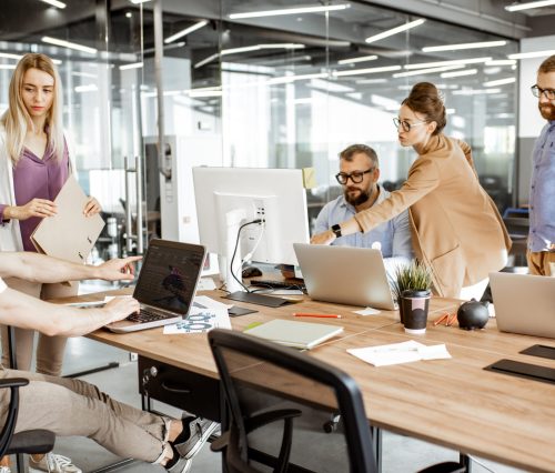 Group of diverse colleagues working on the computers in the modern office or coworking space, bearded hipster as a programmer writing code