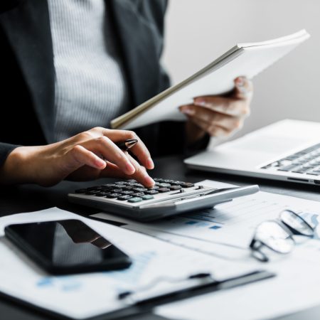 Close up of businesswomen or accountant using calculator calculate while working analytic business report on the workplace, Planning financial and accounting concept.