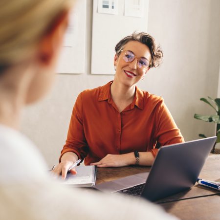 Happy hiring manager smiling while interviewing a job candidate in her office. Cheerful businesswoman having a meeting with a shortlisted job applicant in a creative workplace.